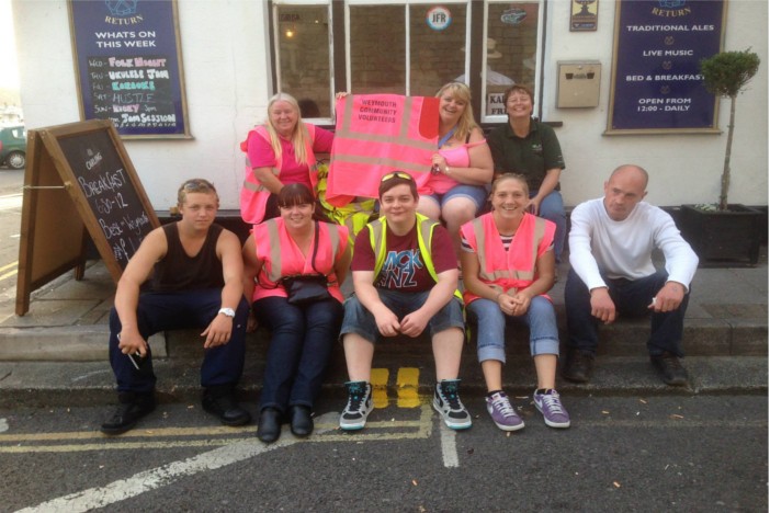 Weymouth Community Volunteers sat on pavement in Weymouth